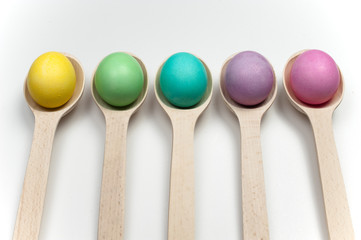 colourfull easter eggs in wooden spoons isolated on white