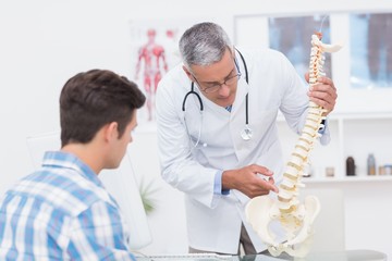 Doctor explaining a spine model to patient - Powered by Adobe