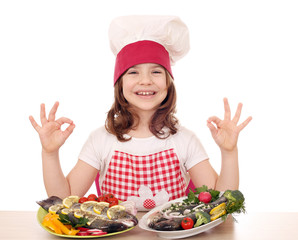 happy little girl cook with fishes and ok hand sign