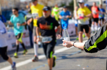 Marathon running race, runners on road, volunteer giving water