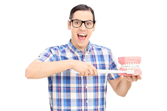 Young guy holding a denture and toothbrush