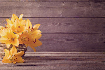 orange lily in basket on wooden background