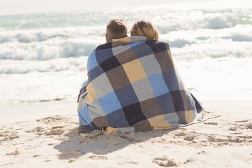 Happy couple wrapped up in blanket
