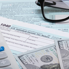 US 1040 Tax Form, calculator, glasses and dollars - studio shot