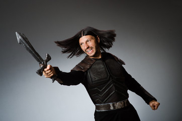 Angry knight with sword against dark background