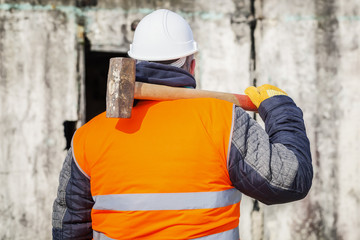 Worker with sledge hammer against the wall
