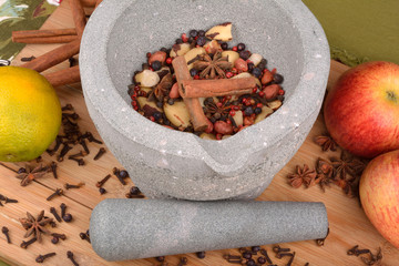 stone pestle grinding anise, nuts, pepper and cloves on wood