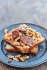 Toast with beans and chorizo on a tin plate.
