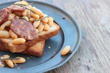 Toast with beans and chorizo on a tin plate.