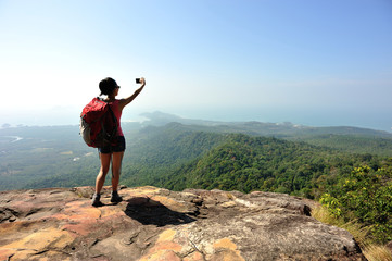 Fototapeta premium woman hiker taking photo at mountain peak cliff