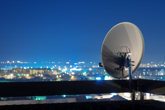 Satellite dish antenna on rooftop at night