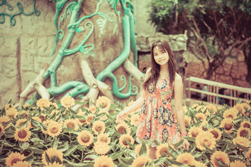 Obraz premium Cute Thai girl standing in the beautiful sunflower scene in vint