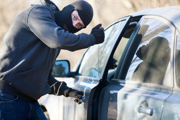 Thief stealing automobile car at daylight street in city