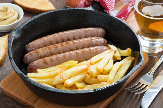 lunch with grilled sausages, French fries, toast and beer