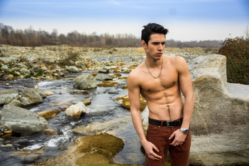 Athletic shirtless young man outdoor at river or water stream