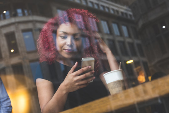 Beautiful girl in a cafe typing on smart phone