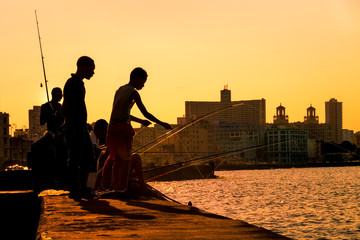 Silhouette of young boys fishing at sunset in Havana
