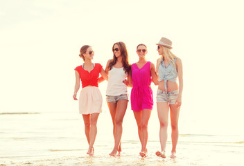group of smiling women in sunglasses on beach