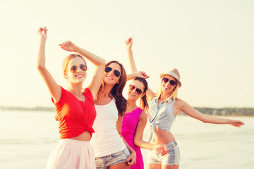 group of smiling women dancing on beach
