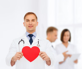 smiling male doctor with red heart and stethoscope