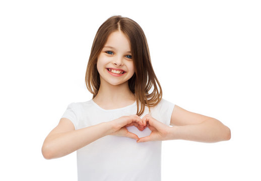 smiling little girl showing heart with hands