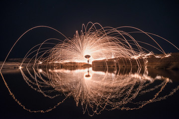 Spinning fire with the reflection in the water