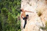Young male rock climber on challenging route on cliff