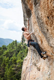 Young male rock climber on challenging route on cliff
