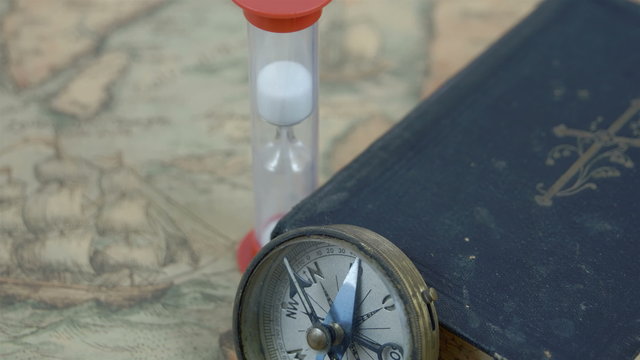 A compass hourglass and a bible on a map