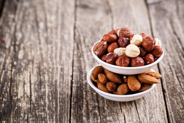 Hazelnuts and almonds on white plates.