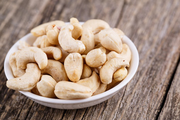 Cashew nuts on a plate on wooden background.