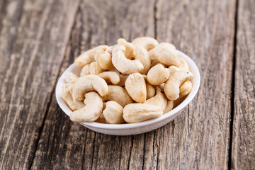 Cashew nuts on a plate on wooden background.