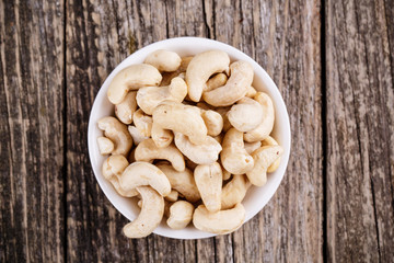 Cashew nuts on a plate on wooden background.