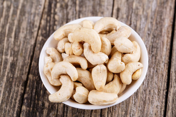 Cashew nuts on a plate on wooden background.