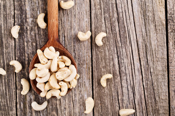 Brazil nuts on a spoon on wooden background.
