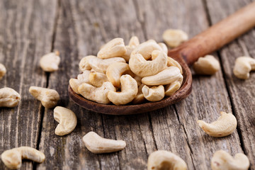 Brazil nuts on a spoon on wooden background.