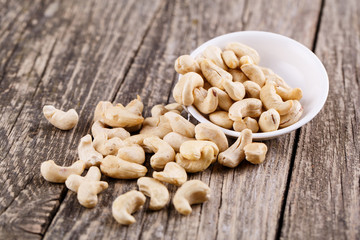 Brazil nuts on a spoon on wooden background.