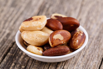 Brazil nuts on a spoon on wooden background.
