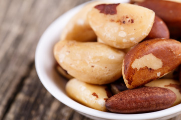 Brazil nuts on a spoon on wooden background.