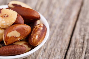 Brazil nuts on a spoon on wooden background.