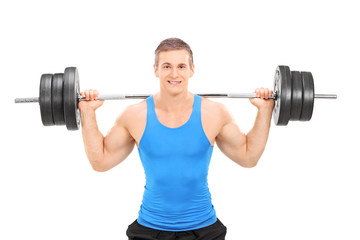 Obraz premium Young smiling athlete in blue shirt exercising with a heavy weig