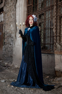 Gothic redhead woman walking with candle