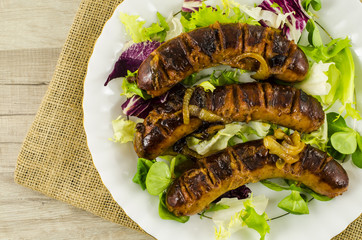 Roasted sausage with vegetables on wooden table