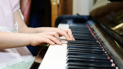 Obraz premium Girl's hands and piano keyboard close-up view