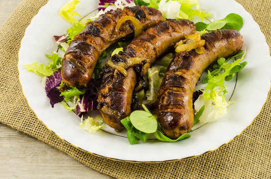 Roasted sausage with vegetables on jute background