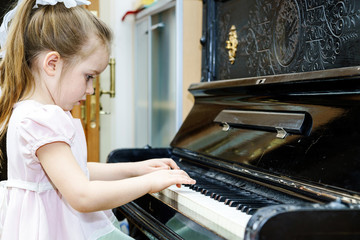 Cute little girl playing old piano