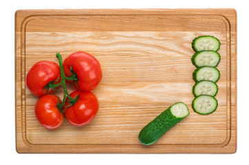 fresh tomatoes and sliced cucumber on a wooden cutting board
