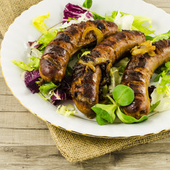 Roasted sausage with vegetables on jute background