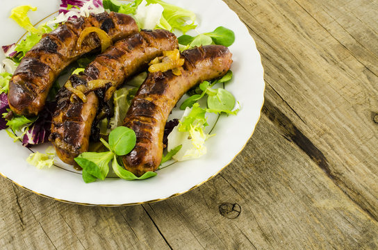 Roasted sausage with vegetables on wooden background