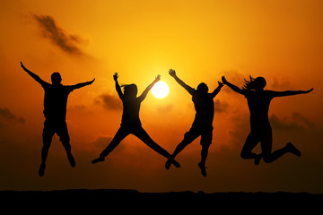 Four friends jumping  at sunset